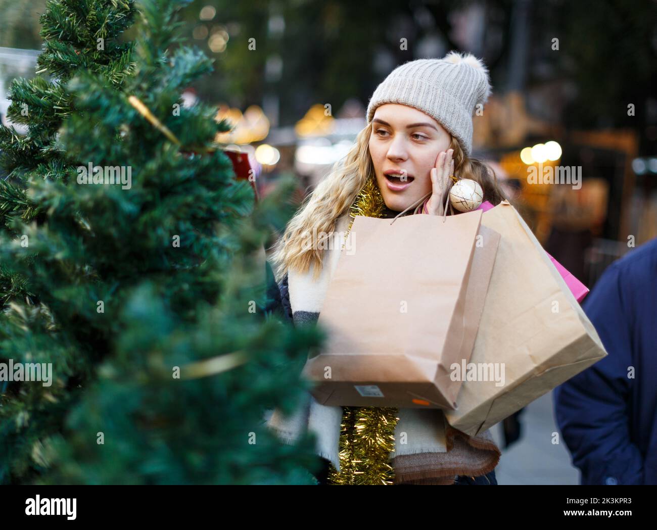 Ragazza in cappello di maglia che sceglie albero di Natale Foto Stock