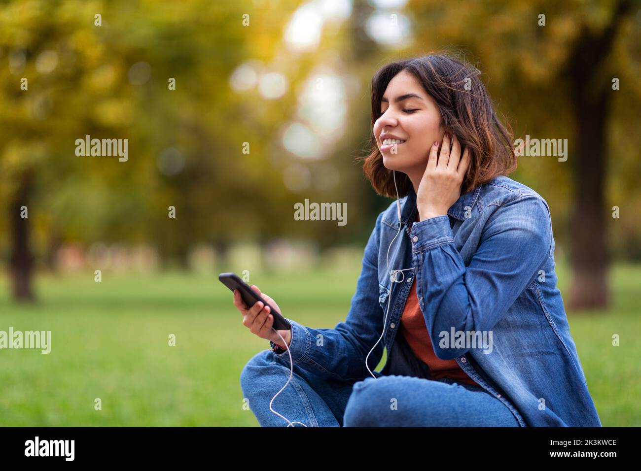 Ritratto di bella giovane donna medio-orientale ascoltare musica con smartphone all'aperto Foto Stock