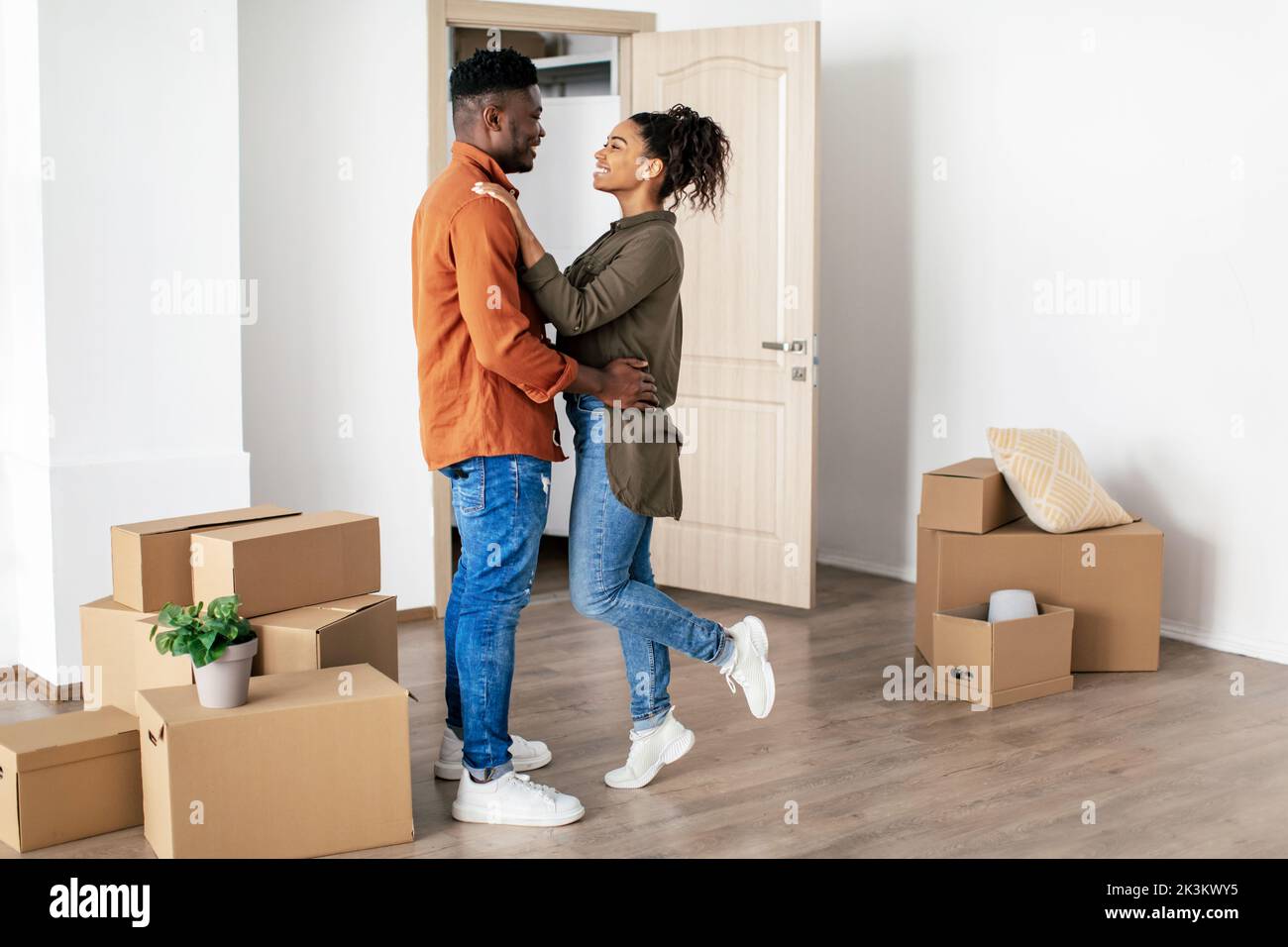 Happy Black Couple che si abbraccia celebrando il movimento propria Casa in piedi al coperto Foto Stock