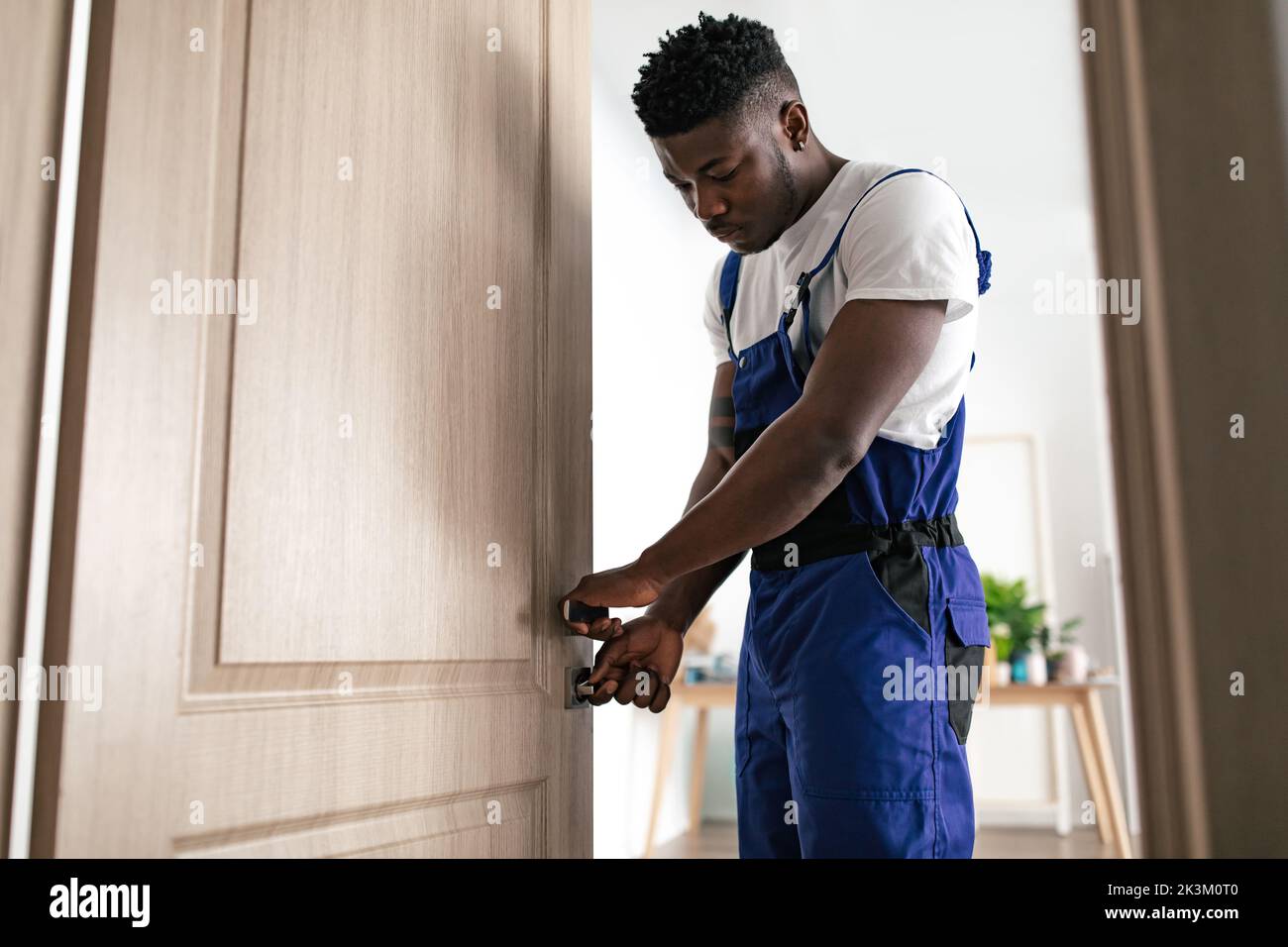 African American Professional riparatore che fissa la serratura della porta a casa Foto Stock