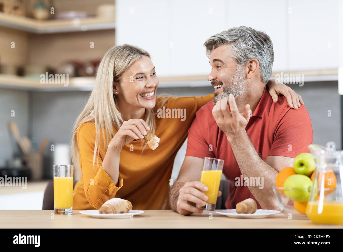 Uomo e donna allegri che hanno uno spuntino e parlano a casa Foto Stock