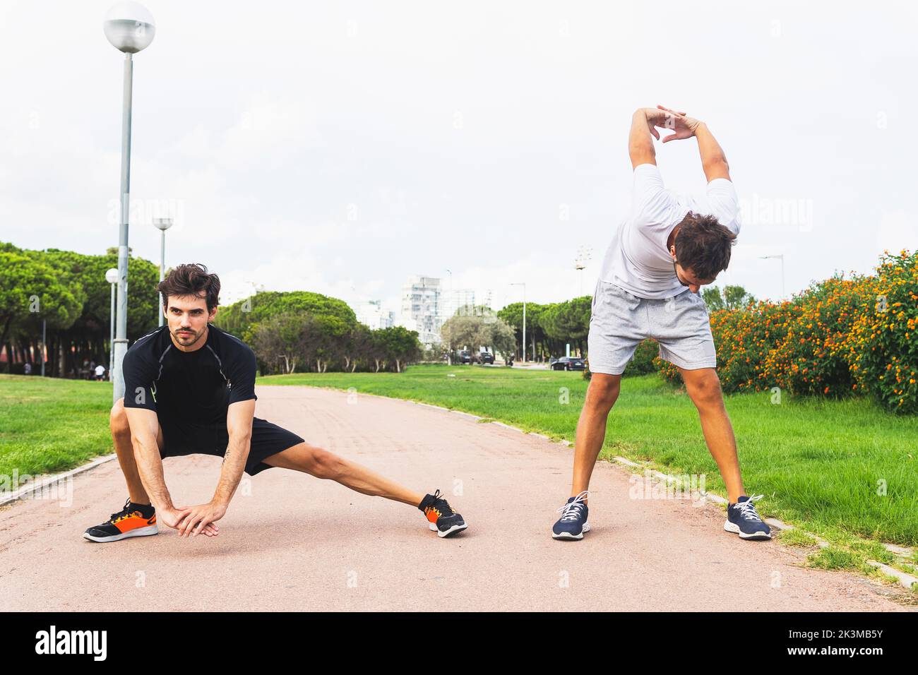 Atleta Hispanic maschile corpo completo affondo e piegarsi in avanti con le mani dietro la schiena mentre si stretching sul percorso durante l'allenamento fitness nel parco Foto Stock