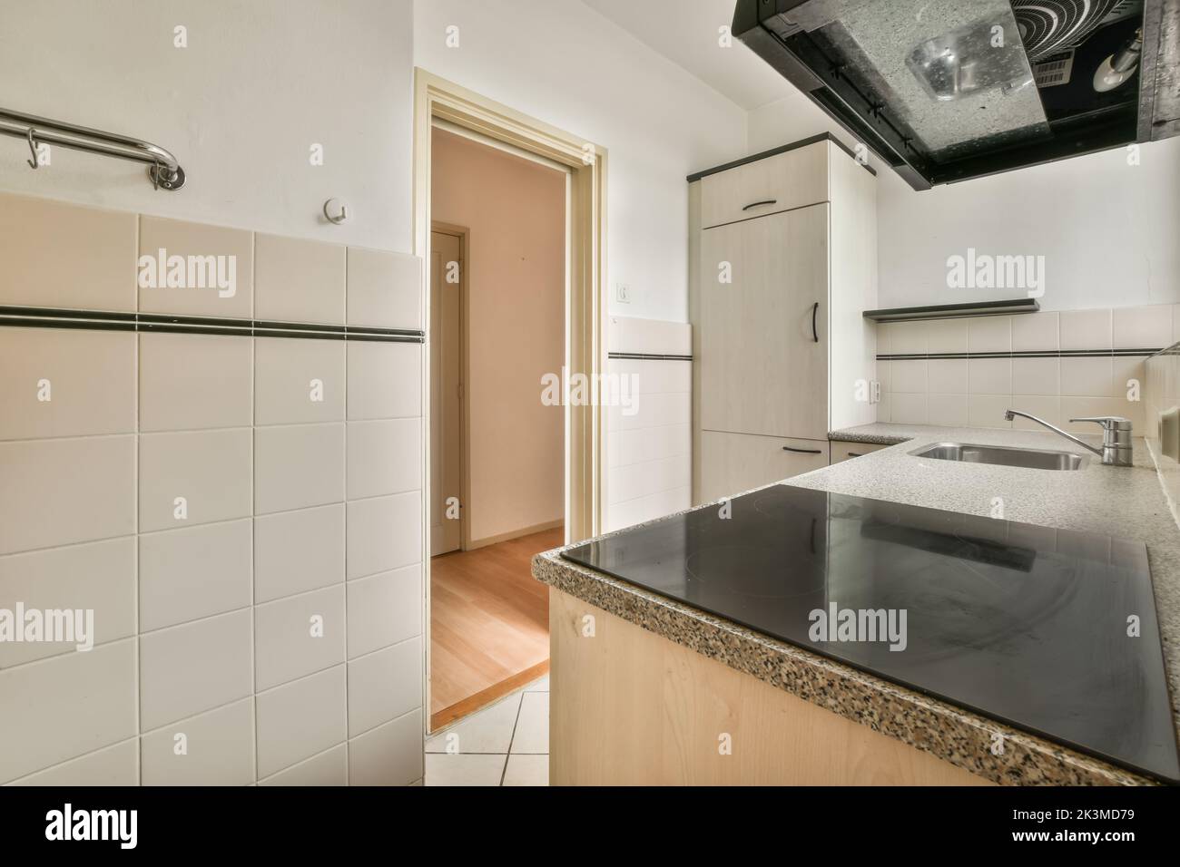 Vecchia cucina con armadi in legno e pareti piastrellate in una cucina luminosa e spaziosa in appartamento Foto Stock