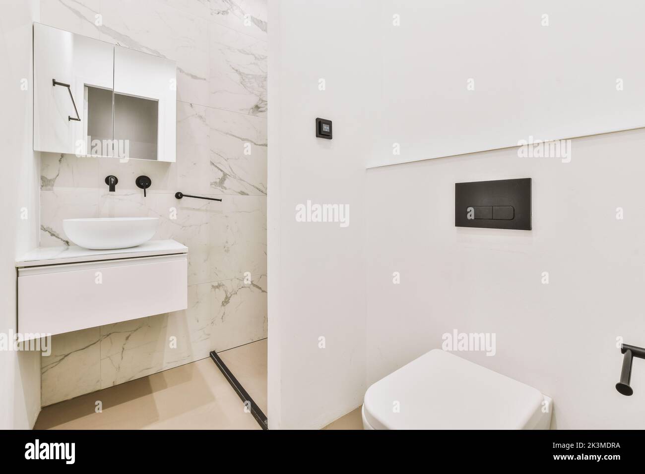 Bagno moderno con lavandino e servizi igienici su pareti piastrellate in marmo in un bagno contemporaneo Foto Stock
