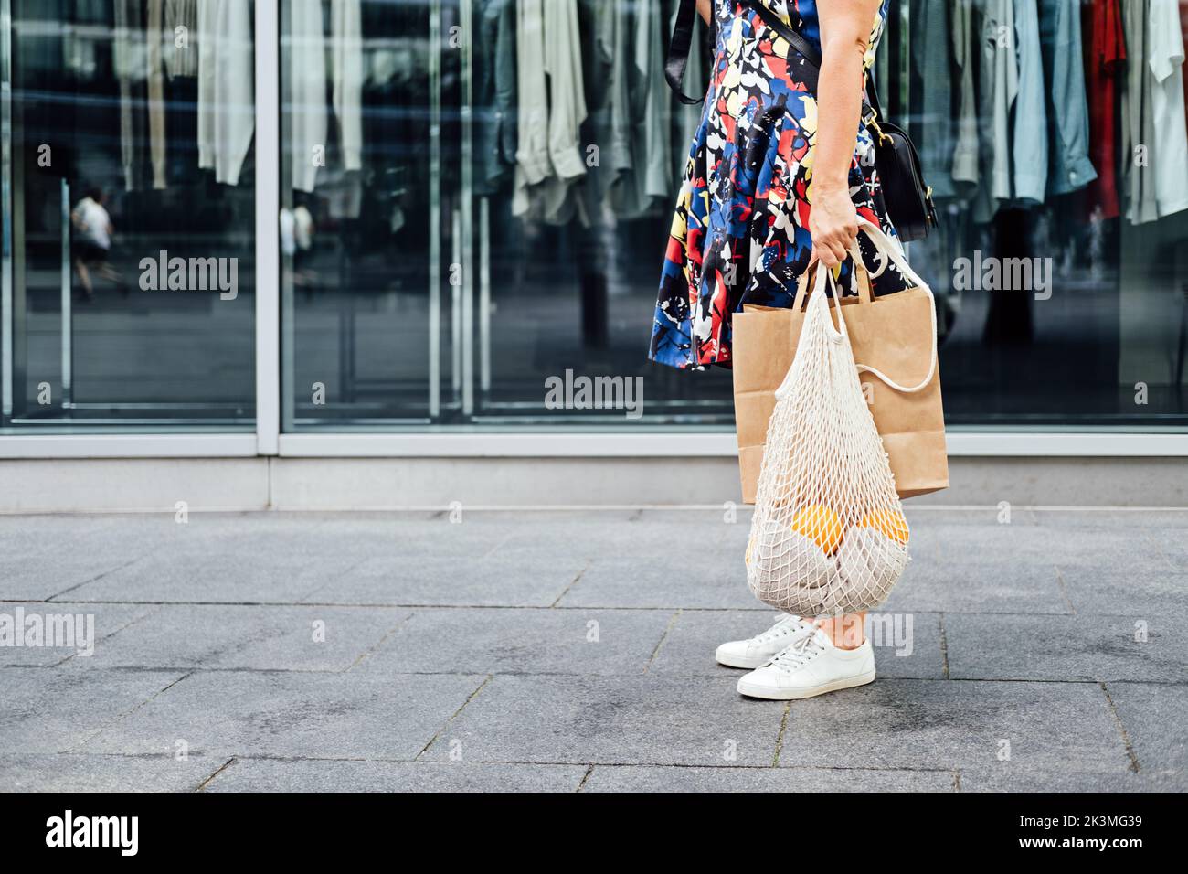Sostenibile Eco friendly Slow Fashion Shopping. Ritratto di donna senza volto con borsa in rete bianca riutilizzabile in tela e borsa della spesa in carta nel negozio di abbigliamento Foto Stock
