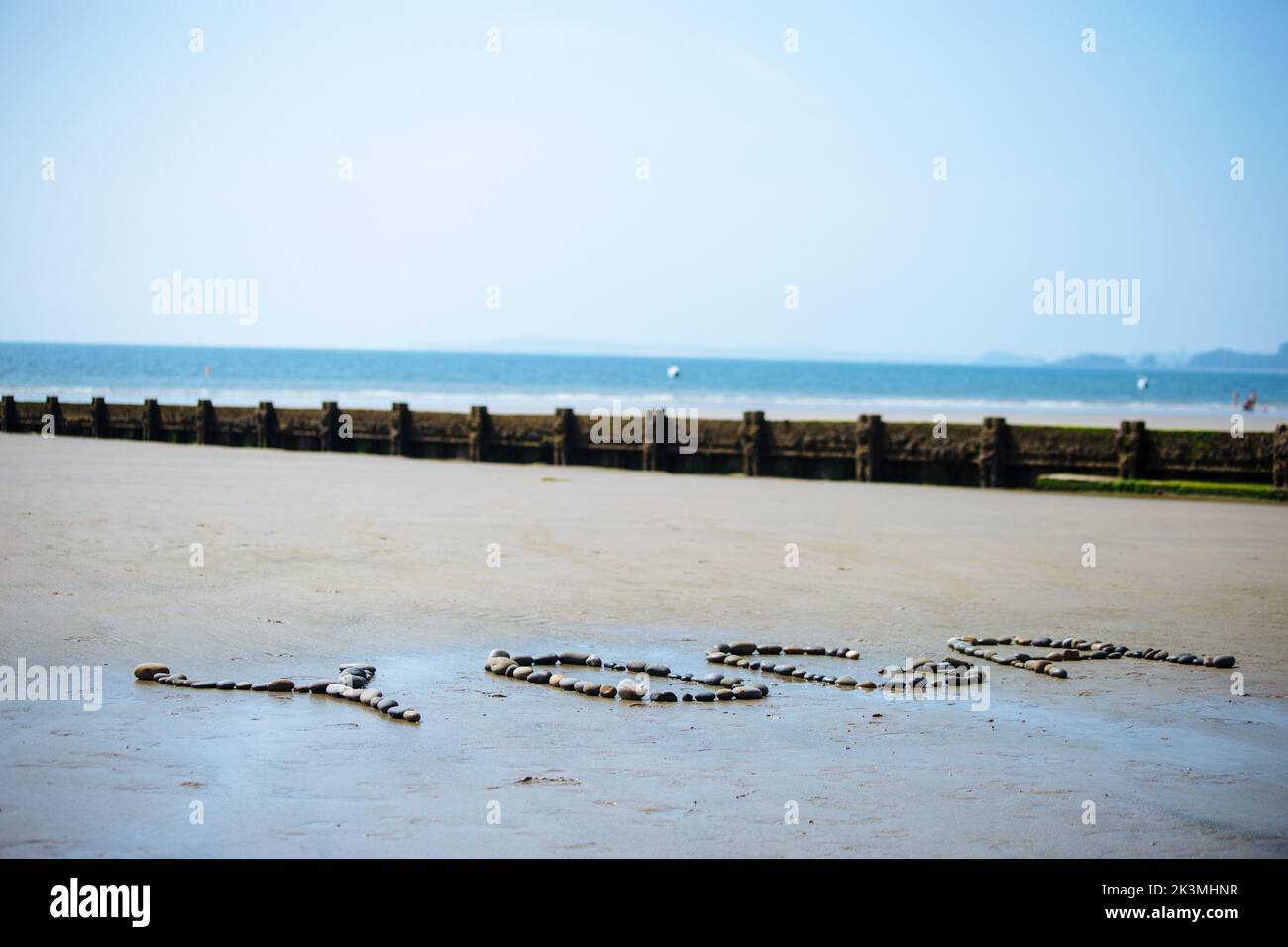 Un primo piano dello Yoga scritto sulla spiaggia con ciottoli e conchiglie Foto Stock