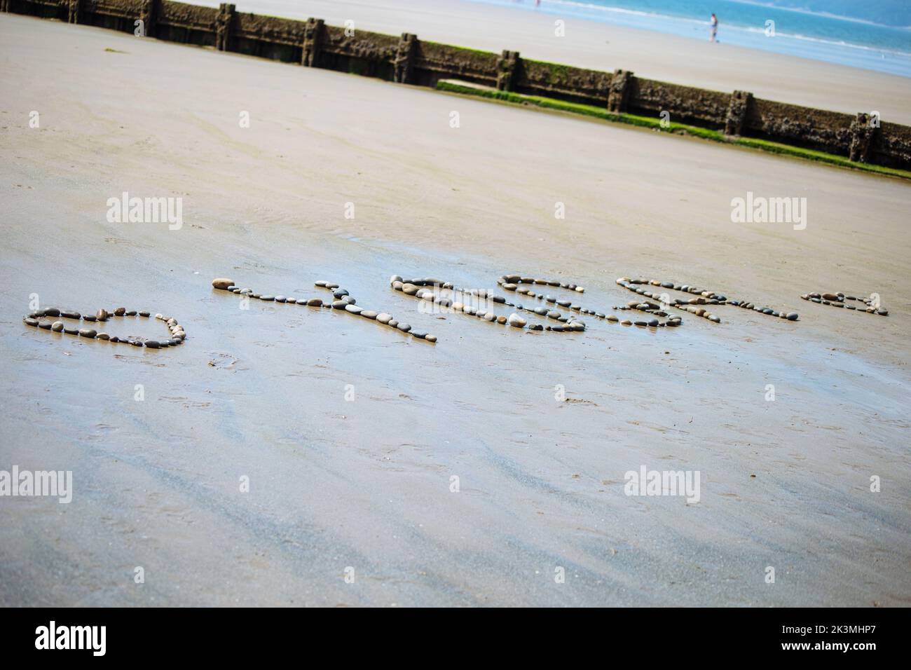 Un primo piano dello Yoga scritto sulla spiaggia con ciottoli e conchiglie Foto Stock