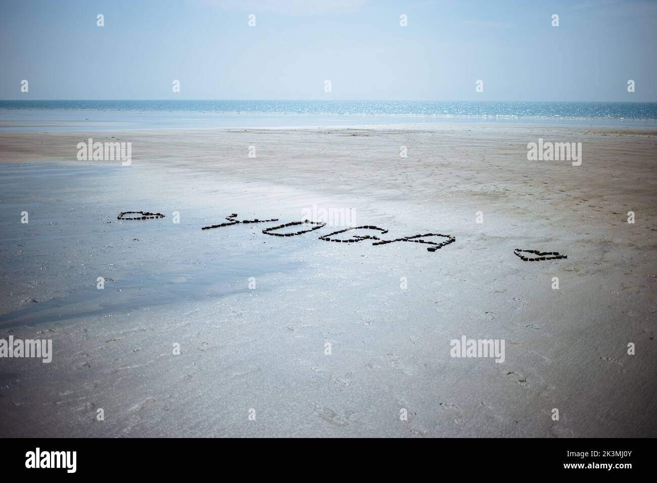 Un primo piano dello Yoga scritto sulla spiaggia con ciottoli e conchiglie Foto Stock