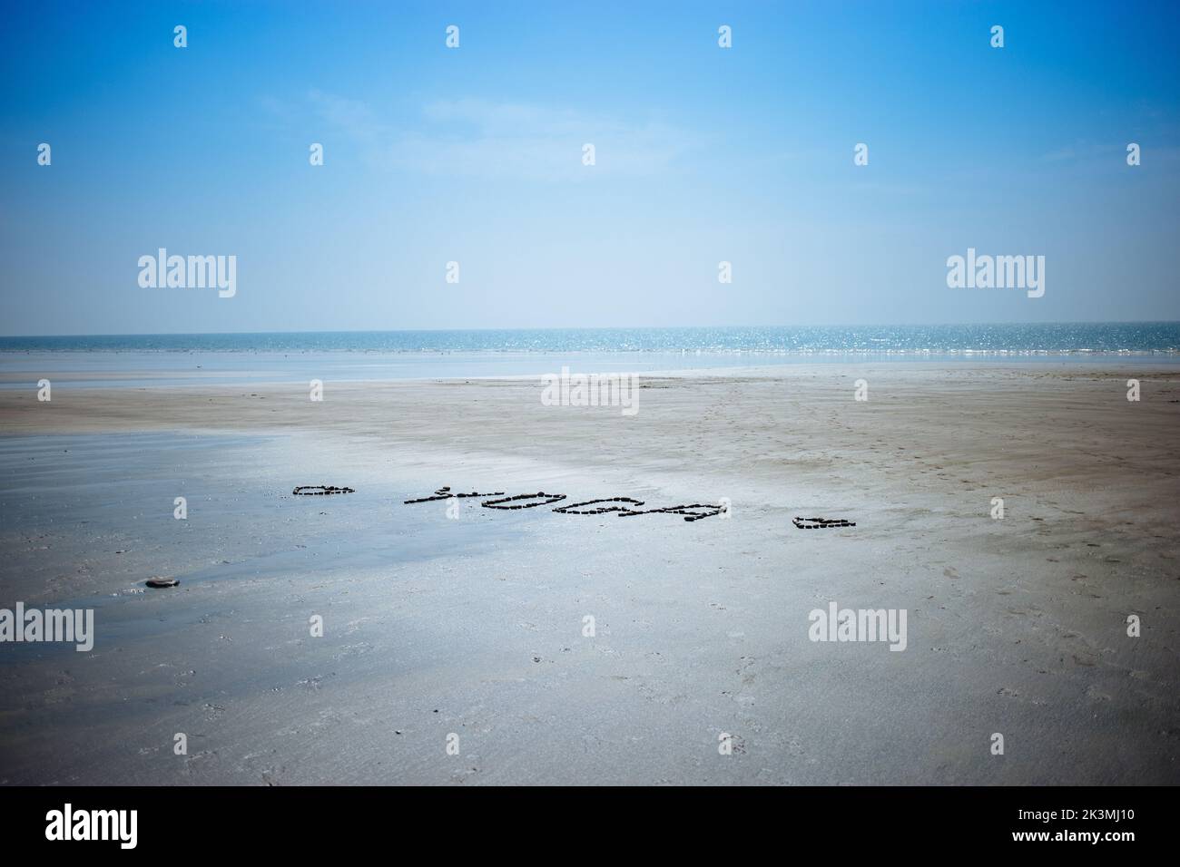 Un primo piano dello Yoga scritto sulla spiaggia con ciottoli e conchiglie Foto Stock