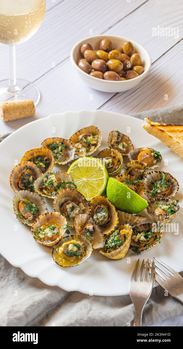 Molluschi di limbano con calce su piatto bianco Foto Stock