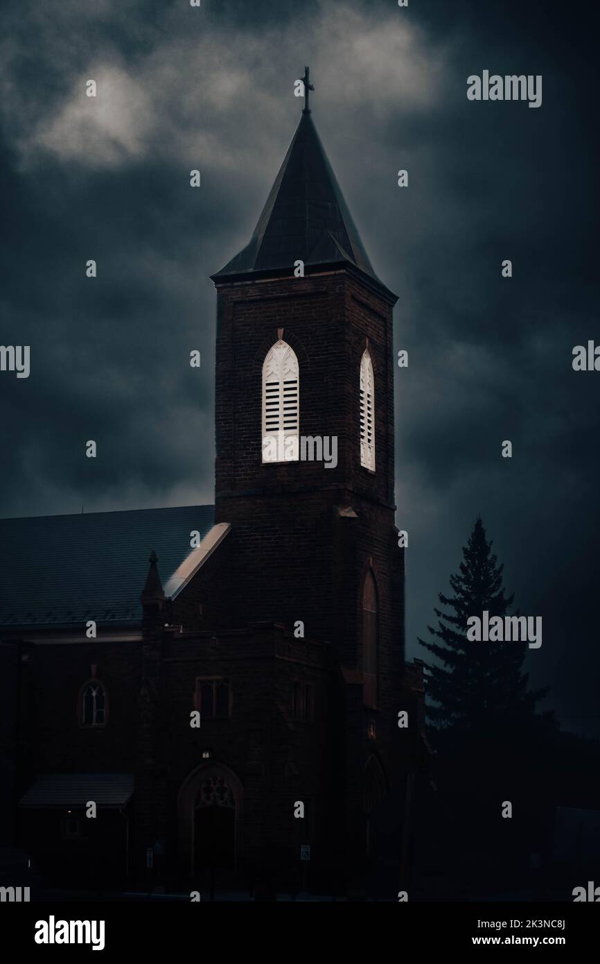 Uno scatto verticale scuro di una chiesa con un overcast Foto Stock