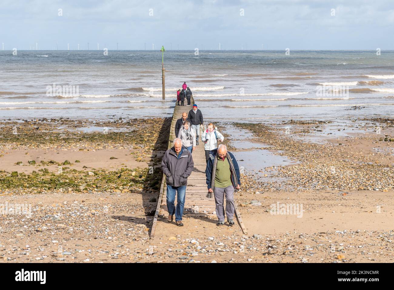 Persone che camminano su un molo sulla spiaggia di Llandudno, Galles del Nord, Regno Unito. Foto Stock