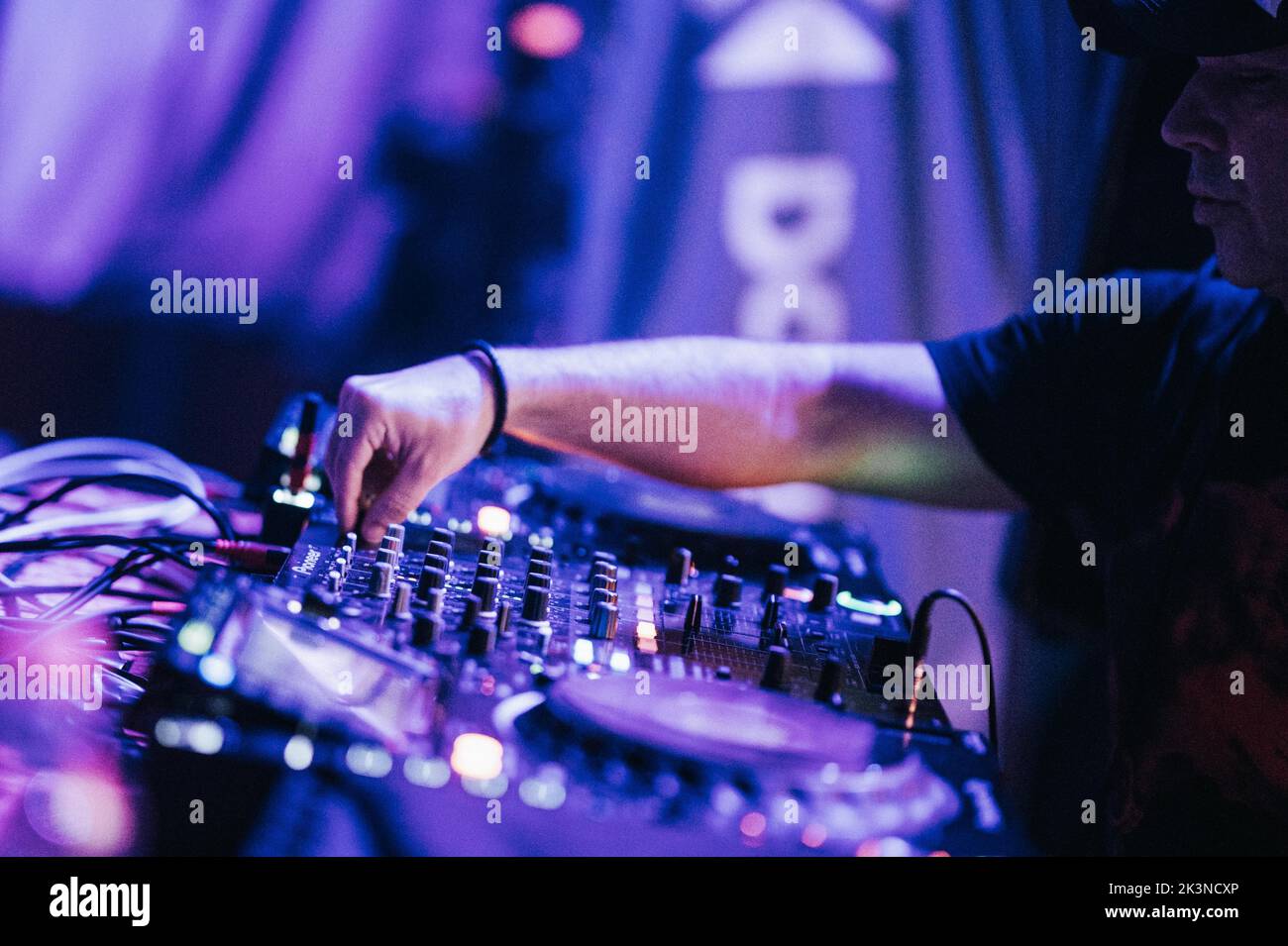 Un primo piano di un DJ che suona musica sul suo mixer in una esecuzione notturna Foto Stock