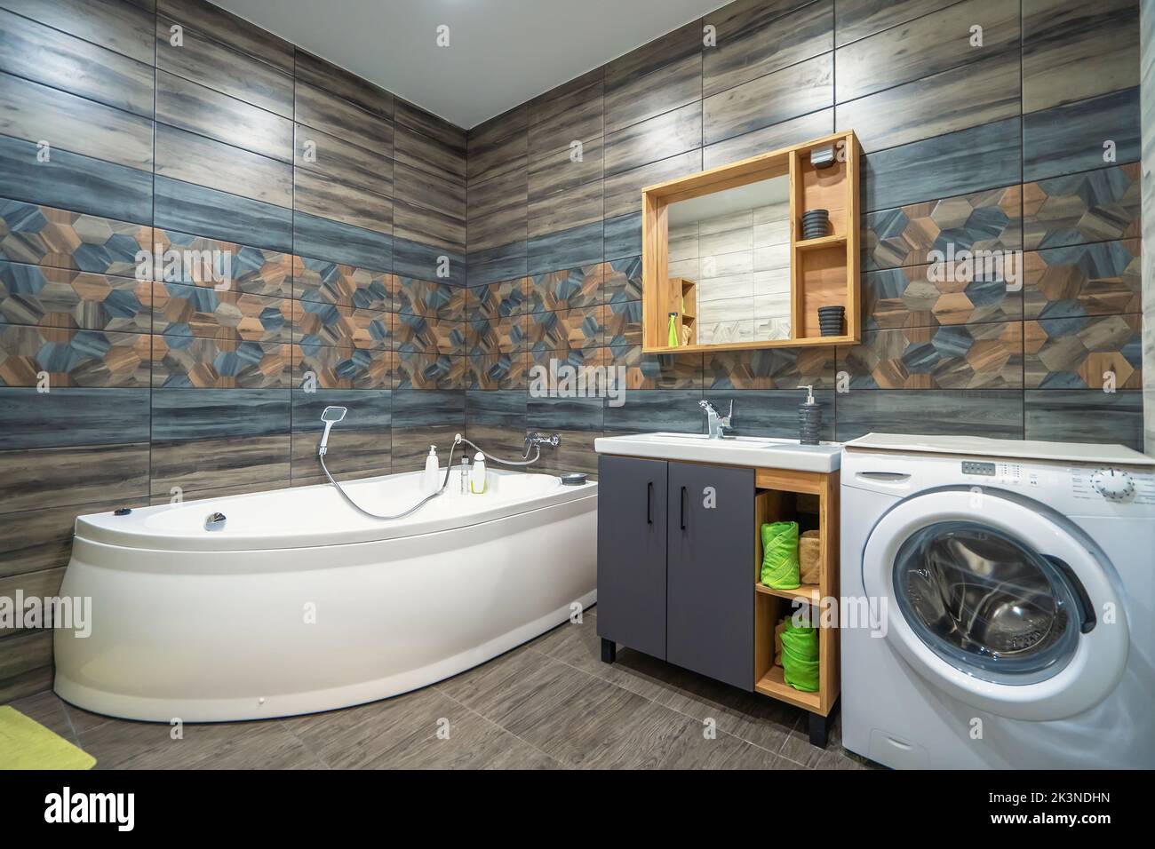 Moderno bagno interno con vasca, specchio, lavabo e lavatrice. Foto Stock