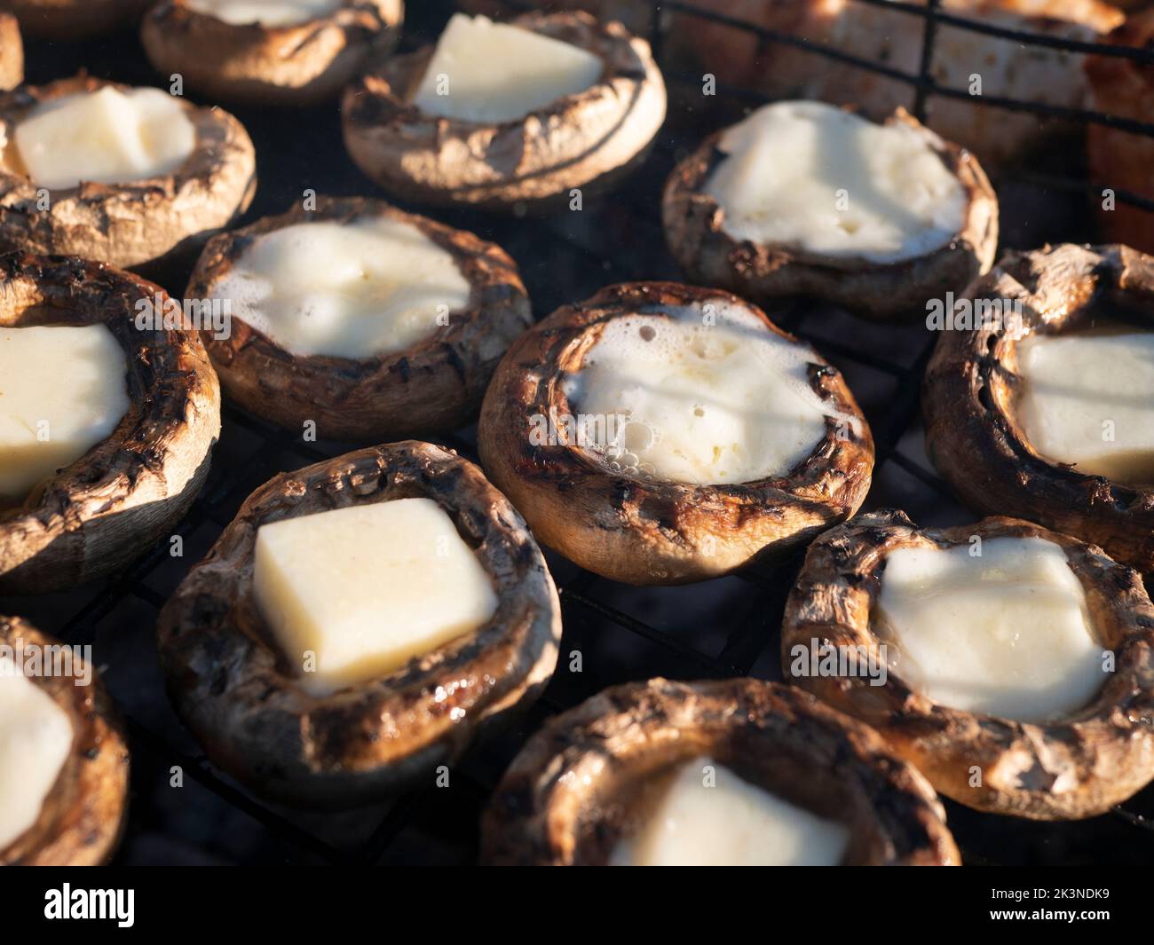 Funghi ripieni di formaggio. Champignons alla griglia ripieni di formaggio, focus selettivo. Tazze di portobello calde con mozzarella fusa sulla griglia Foto Stock