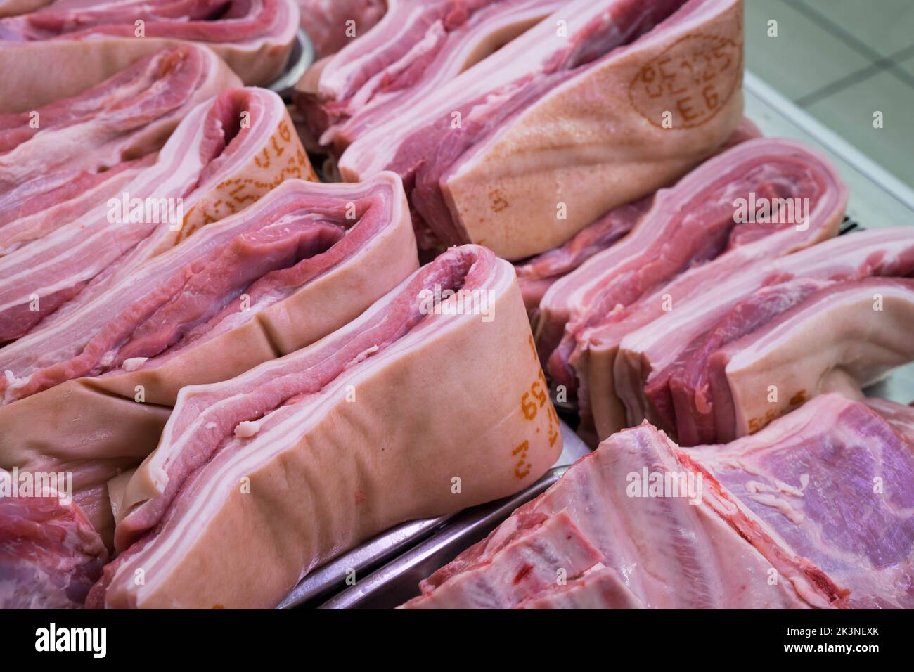 Strisce di pancie di maiale tagliate in misura pronta per la vendita in un macellaio Londra Inghilterra UK Foto Stock