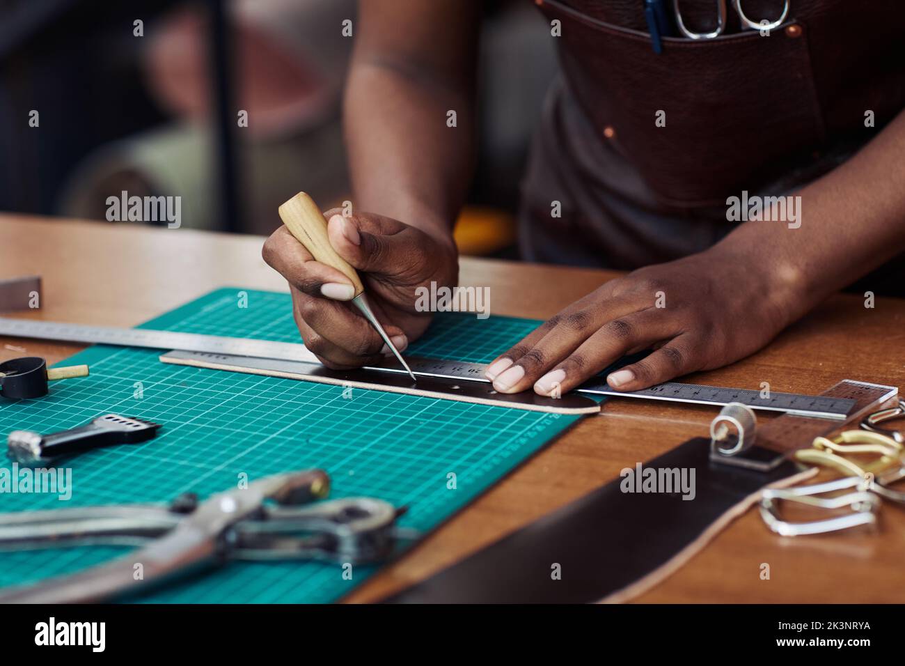 Primo piano di buchi artigianali neri in cintura artigianale in bottega di pelletteria, spazio copia Foto Stock