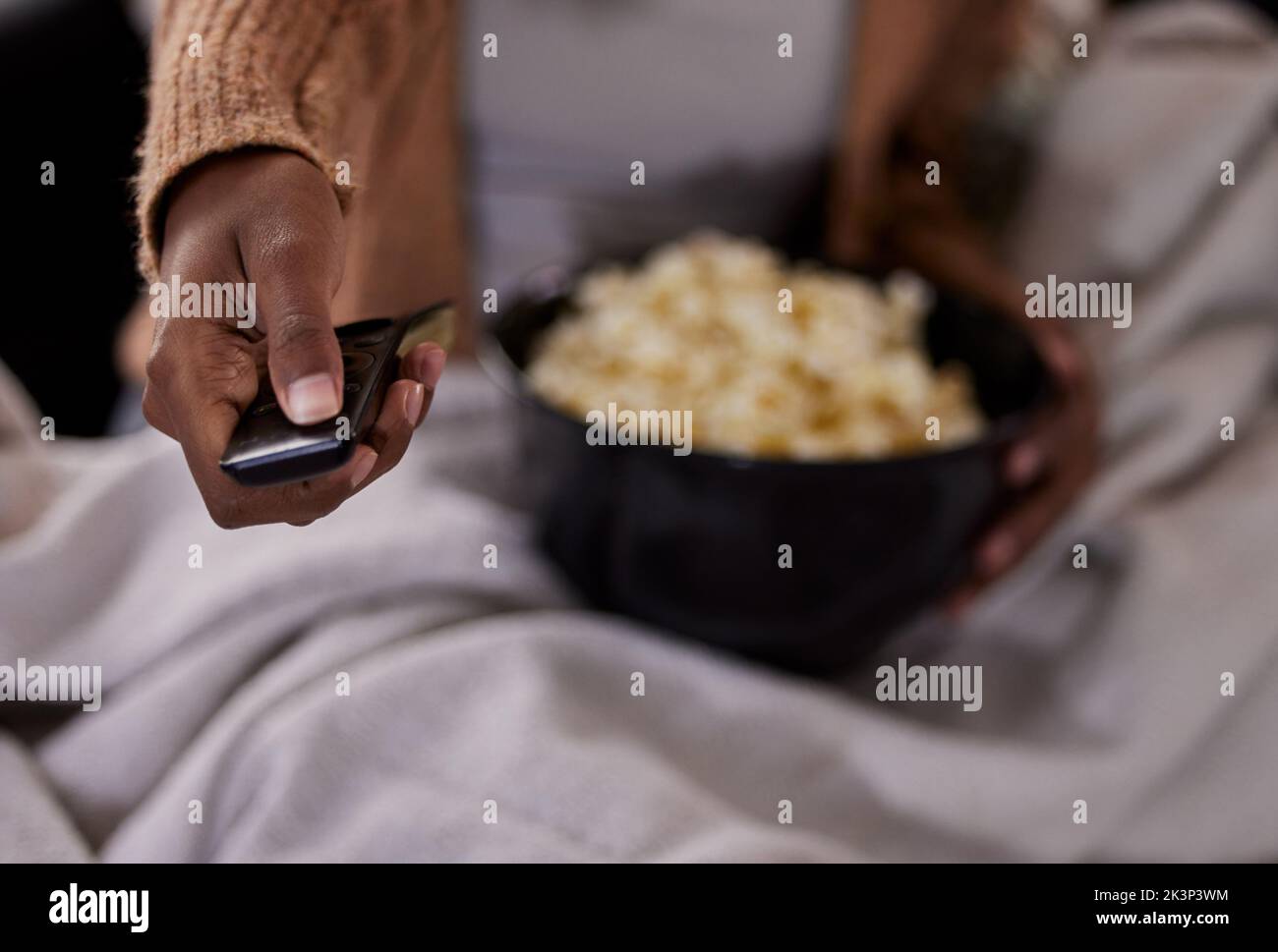 Ora TV. Ripresa ad alta angolazione di una donna irriconoscibile che mangia popcorn mentre guarda la tv a casa. Foto Stock