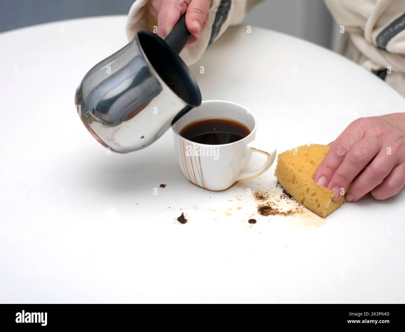 Donna e caffè appena versato sul tavolo, in primo piano al coperto Foto Stock