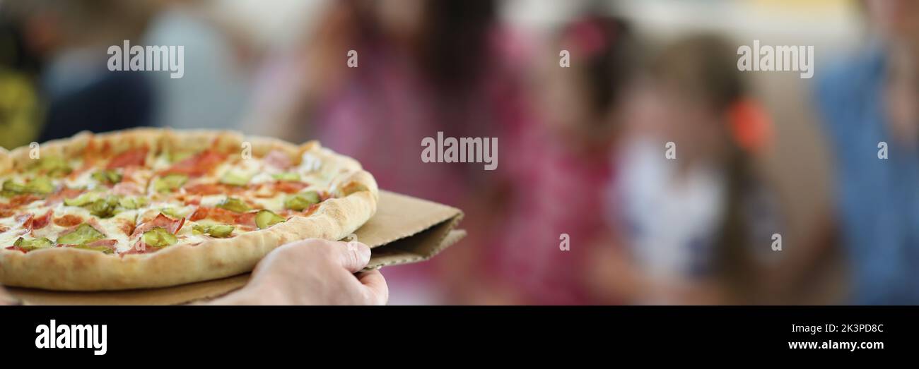 L'uomo porta la pizza grande calda con ripieno e salsa Foto Stock