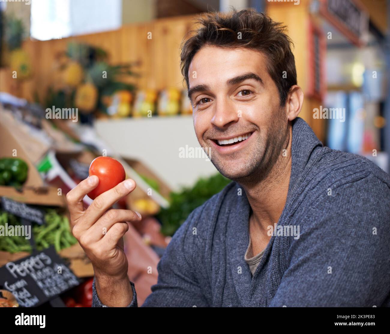 Maturo e delizioso. Primo piano ritratto di un giovane uomo che acquista pomodori in un negozio di alimentari. Foto Stock Maturo e delizioso. Primo piano ritratto di un giovane uomo che acquista pomodori in un negozio di alimentari. Foto Stock