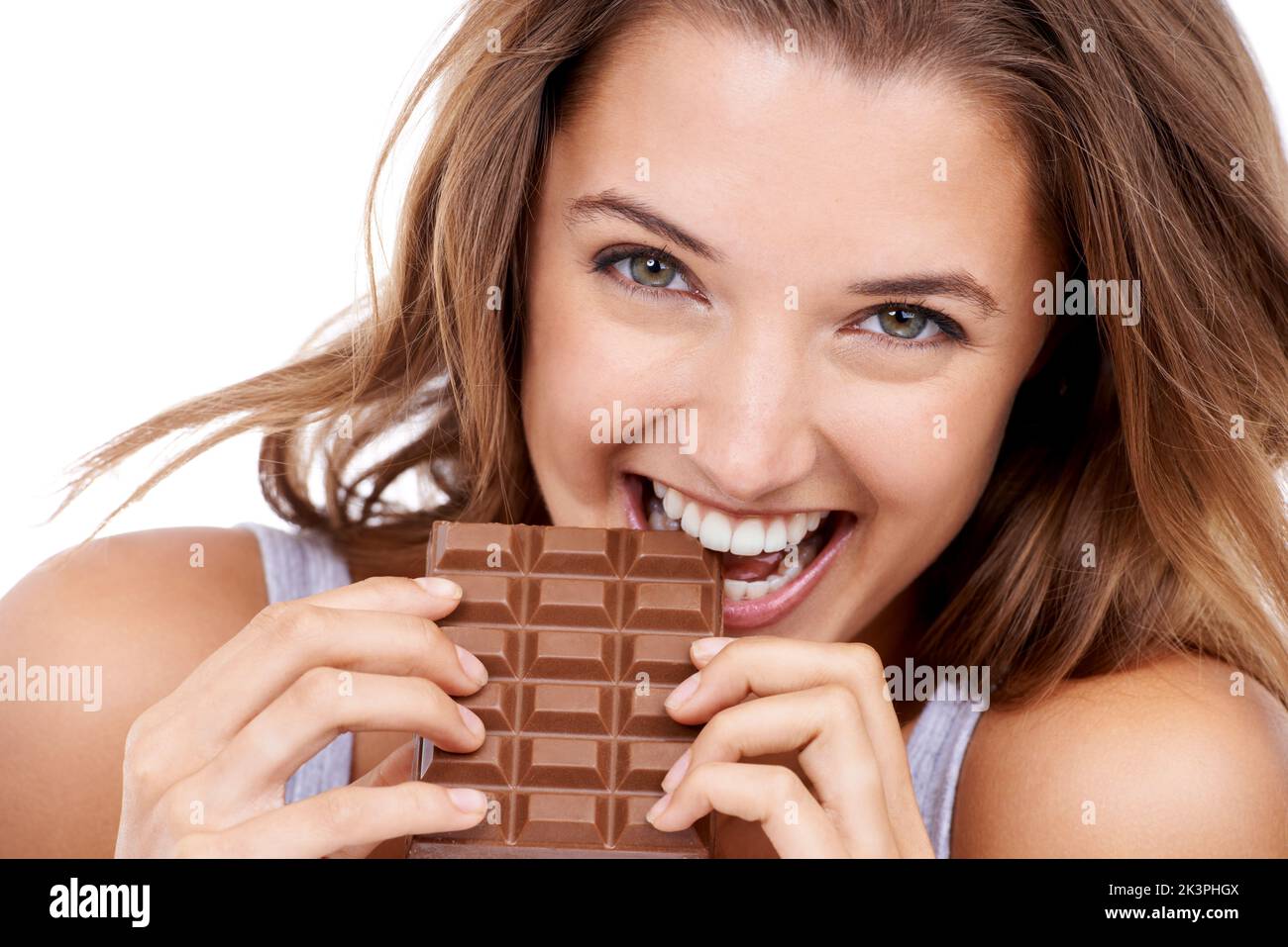 Non posso avere solo un morso. Una giovane donna attraente che mangia una lastra di cioccolato. Foto Stock
