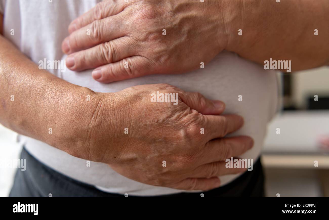 Una persona che tiene lo stomaco che soffre di dolore allo stomaco. Foto Stock