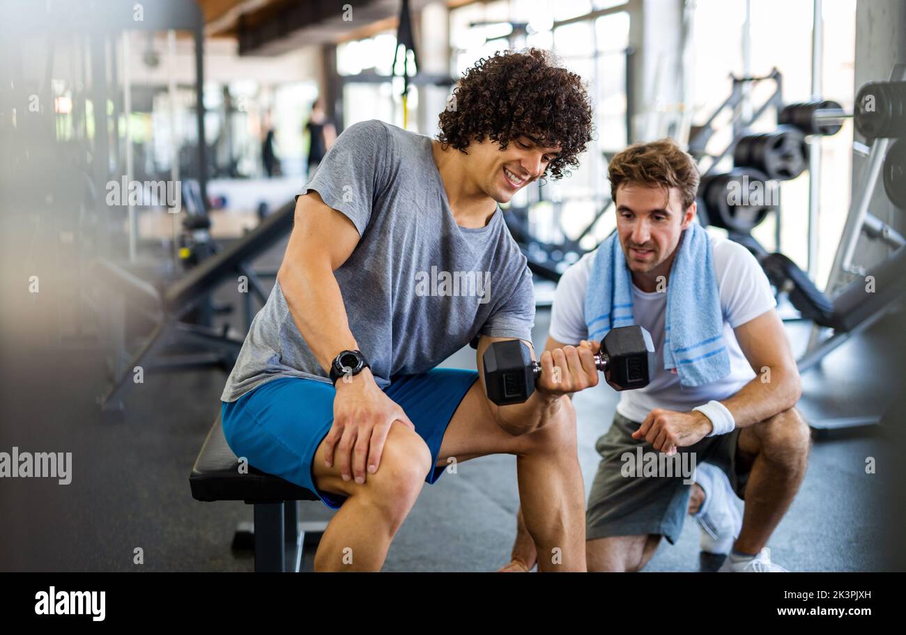 Concetto di fitness, sport, esercizio fisico. Allenare l'uomo con il suo personal trainer in palestra. Foto Stock