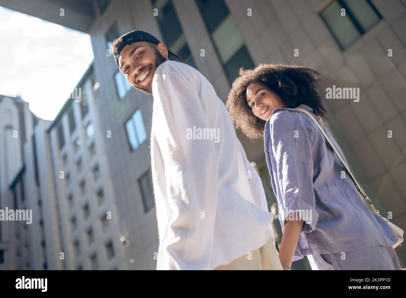 Giovane coppia che cammina per strada e tiene le mani Foto Stock