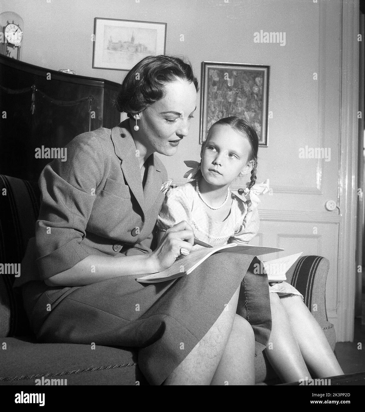 Negli anni '1950s. Modello professionale di moda Mey-Birgit Attaque con sua figlia Monica facendo i compiti insieme. Si siedono da vicino e hanno i suoi libri di scuola nei loro giri. Svezia 1954 Kristoffersson Ref BX25-8 Foto Stock