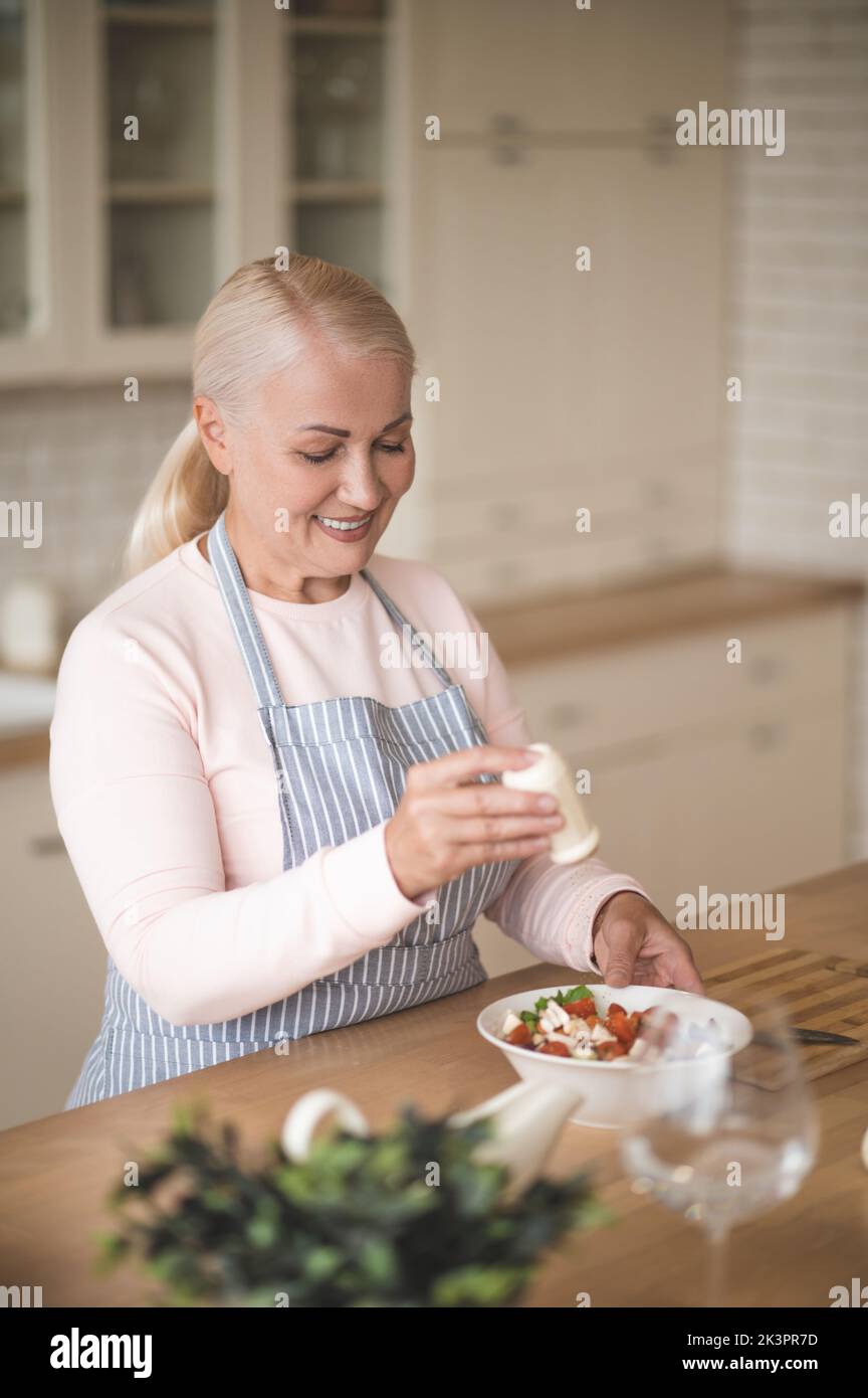 Cuoco femminile aggiungendo pepe al piatto vegetariano Foto Stock