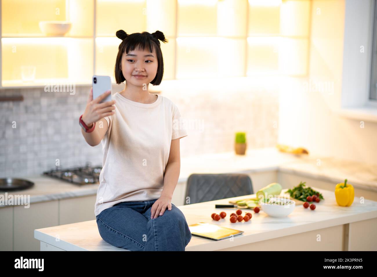 Ragazza che prende un selfie in cucina Foto Stock