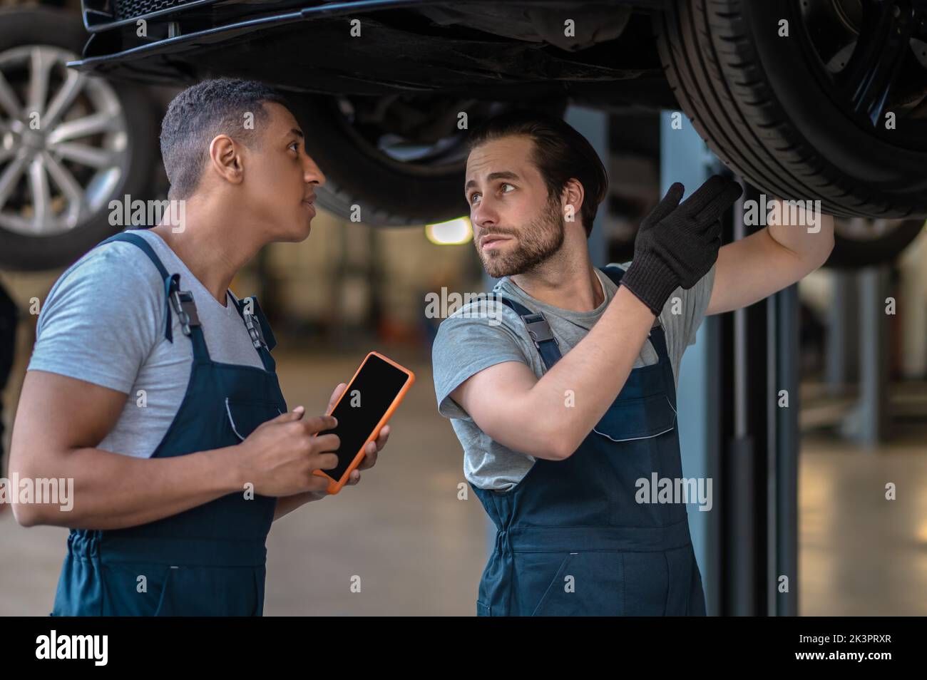 Meccanici esperti che controllano gli pneumatici sul veicolo del cliente Foto Stock