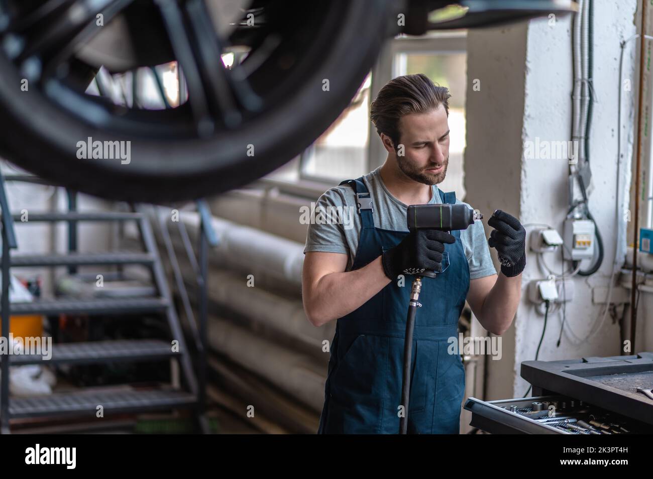 Addetto all'assistenza che lavora nell'officina di riparazione auto Foto Stock