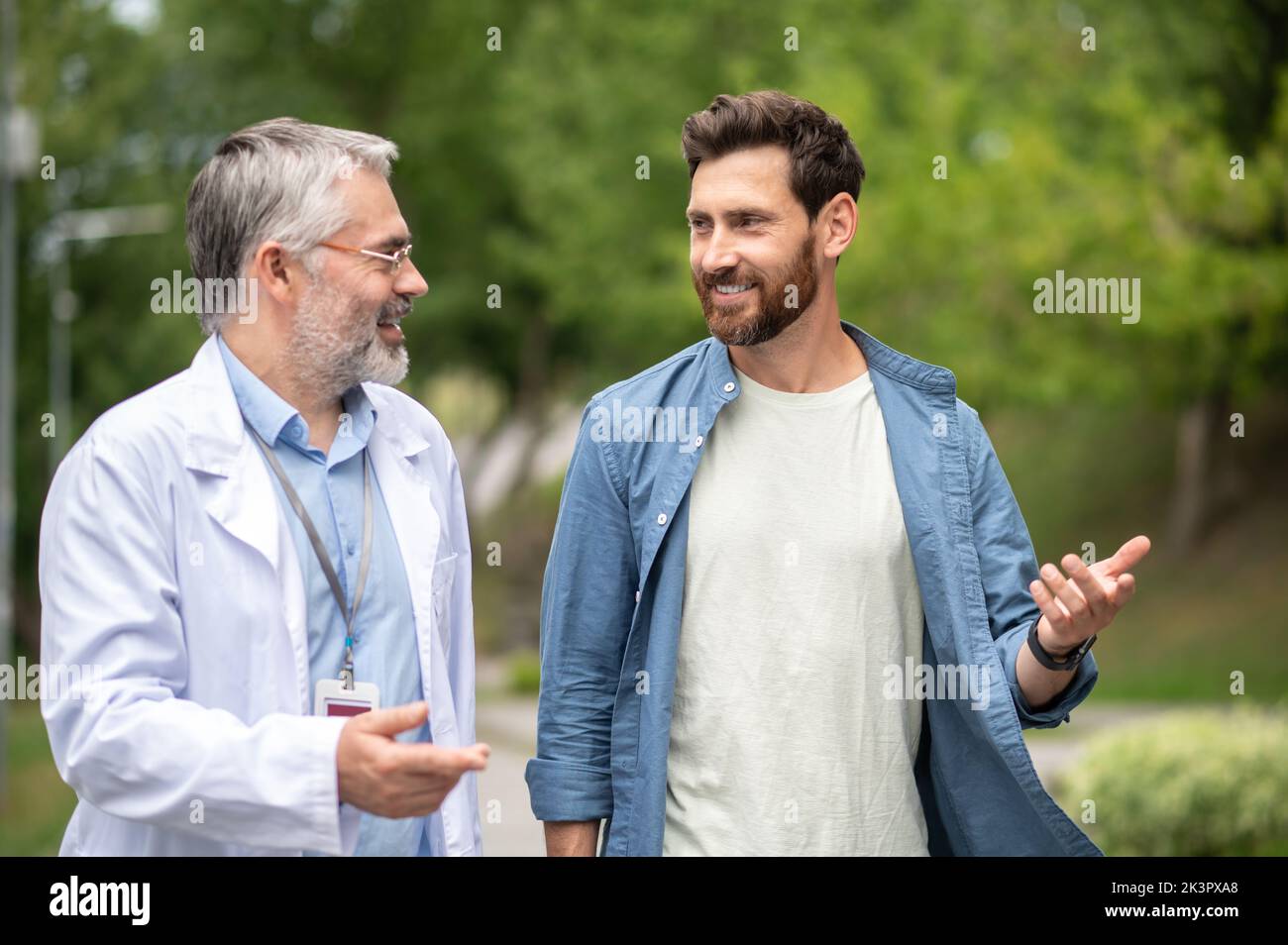 Giovane uomo che parla con un medico esperto maturo in un camice da laboratorio Foto Stock
