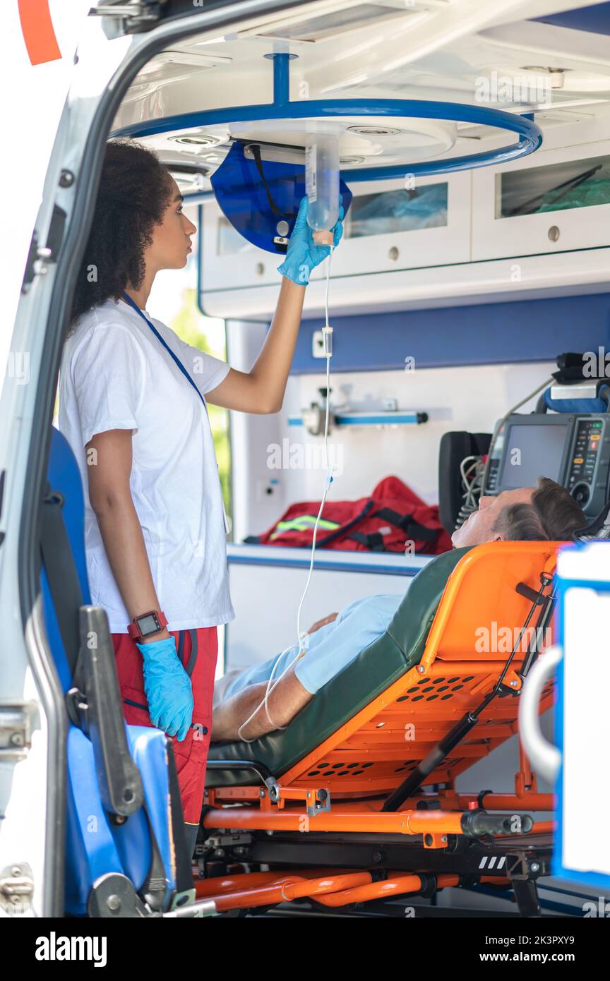 Professionista paramedico che prepara il paziente per una procedura di infusione endovenosa Foto Stock