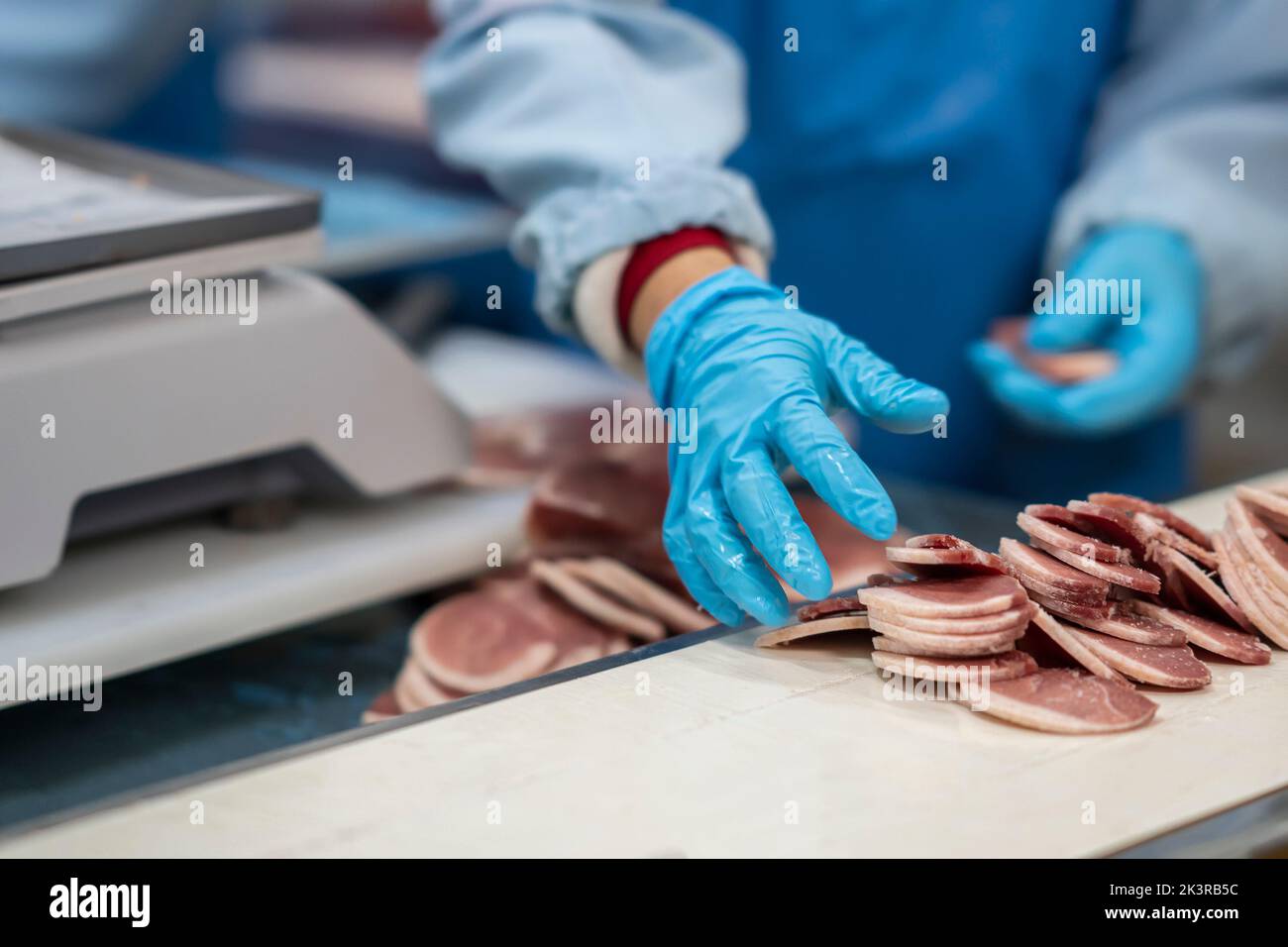 Sezione centrale dei macellai che tagliano la carne e controllano il peso della carne presso la fabbrica di carne. Foto Stock