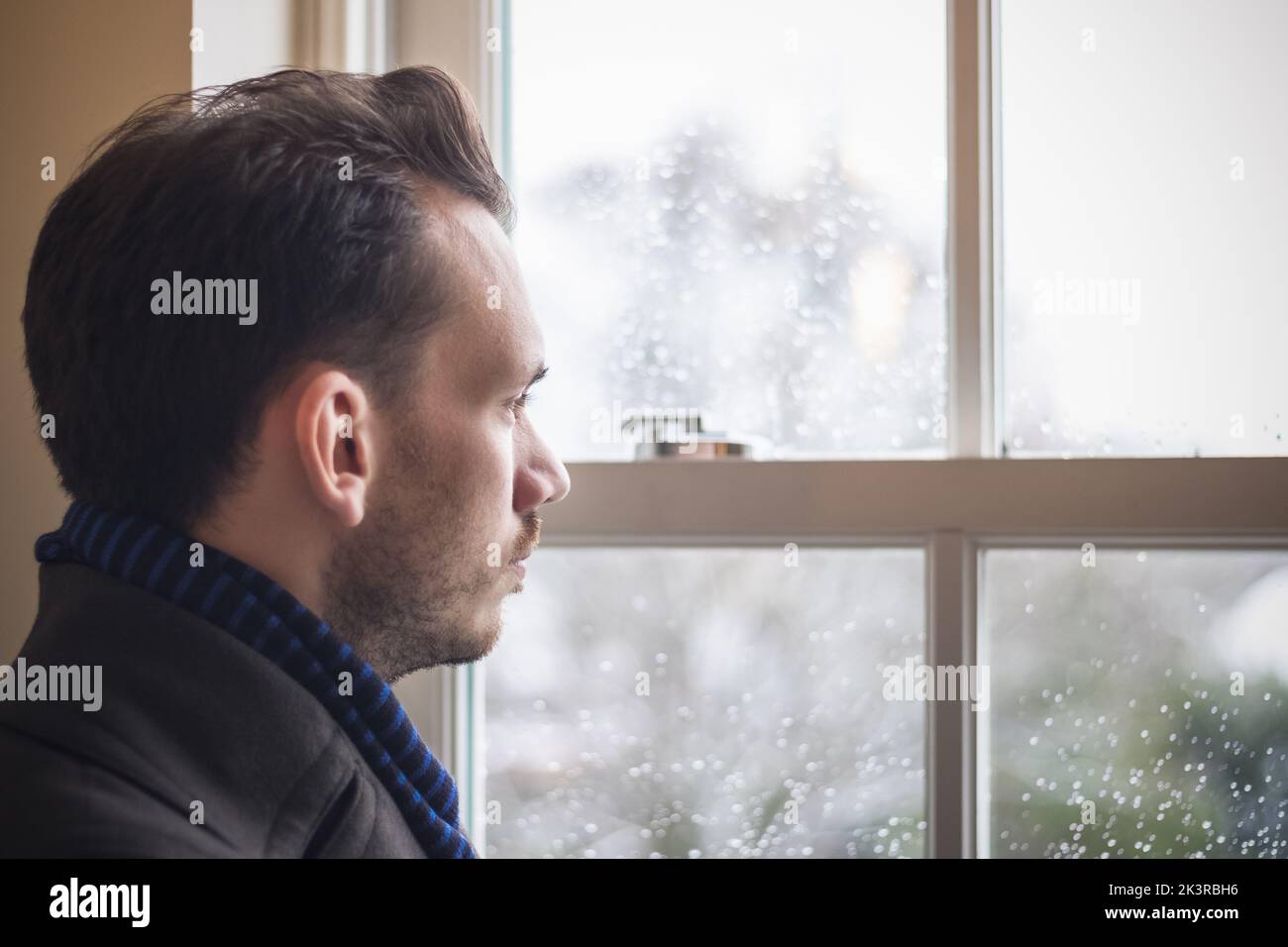Ritratto di un uomo che guarda fuori finestra Foto Stock