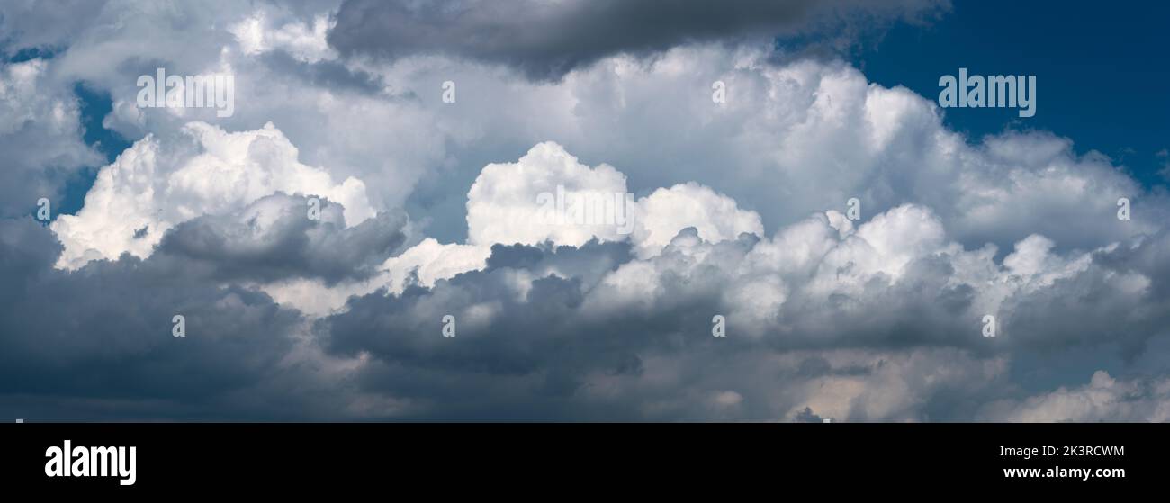 Grandi nuvole luminose contro il cielo blu scuro, nuvola in luce drammatica, vista panoramica Foto Stock