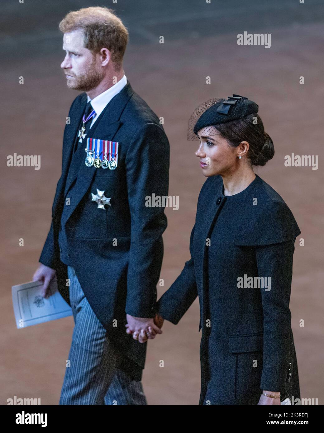 Il principe Harry e Meghan Markle tengono le mani, il duca e la duchessa di Sussex partono dal servizio per l'arrivo della bara della regina Elisabetta II al Palazzo di Westmin Foto Stock