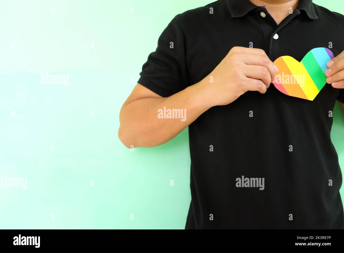 LGBT o LGBTQ amano, sostegno e concetto di accettazione. Giovane asiatico che tiene una forma di cuore di colore arcobaleno sul petto. Foto Stock