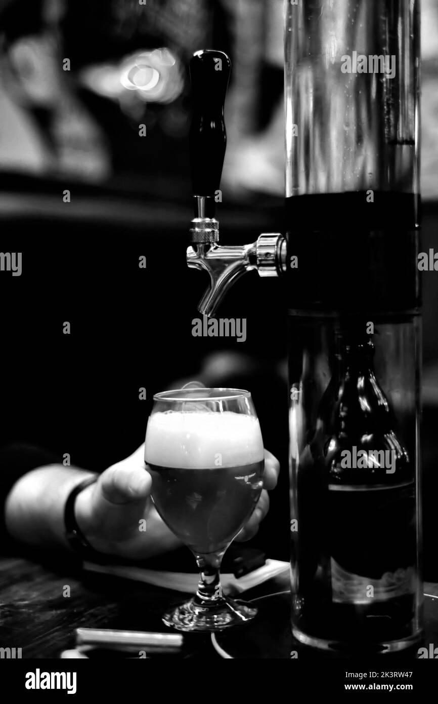 Un primo piano di rubinetto e pinta di birra nel pub in bianco e nero Foto Stock