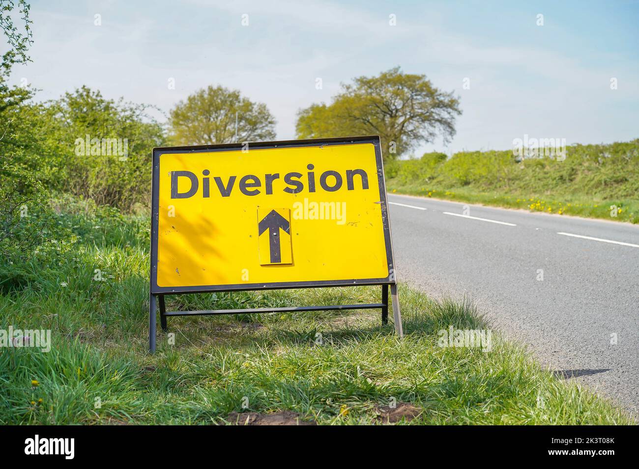Cartello stradale giallo di deviazione, isolato dal lato di una strada di campagna del Regno Unito senza traffico. Foto Stock
