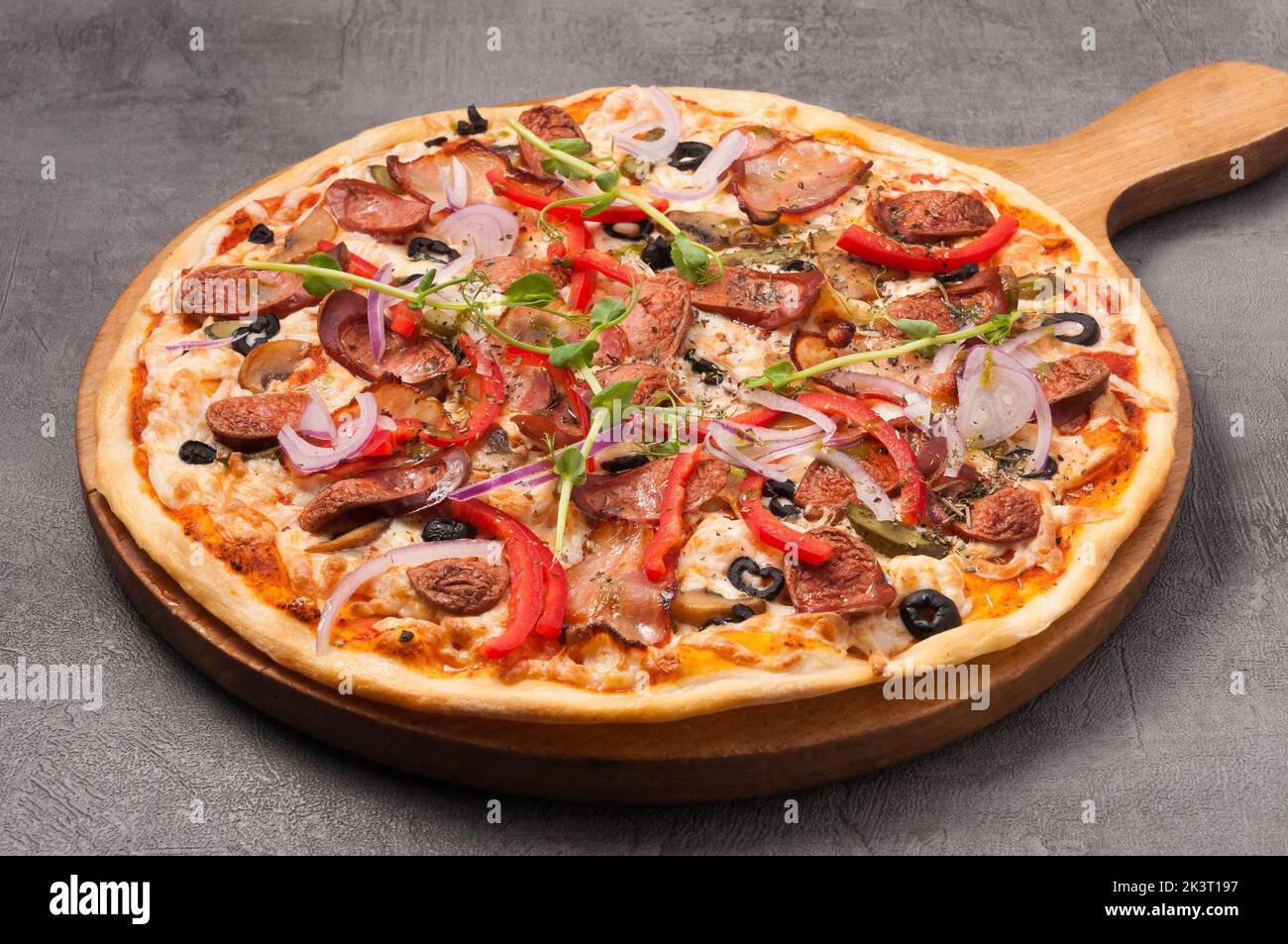 gustosa pizza con pancetta e salsicce da caccia su sfondo grigio Foto Stock