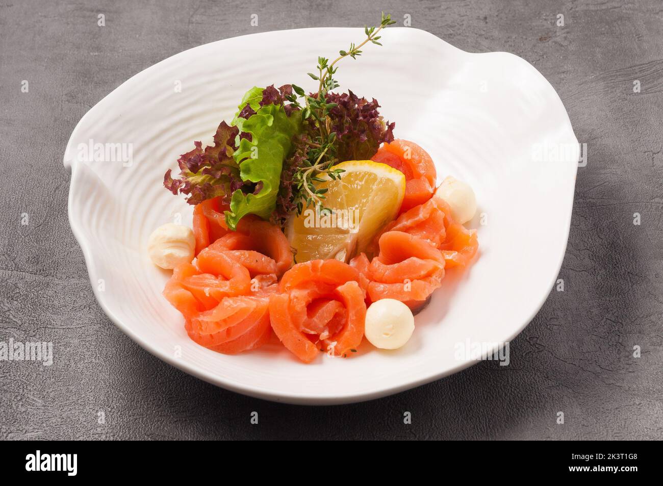 gustoso salmone con burro e limoni su un piatto bianco Foto Stock