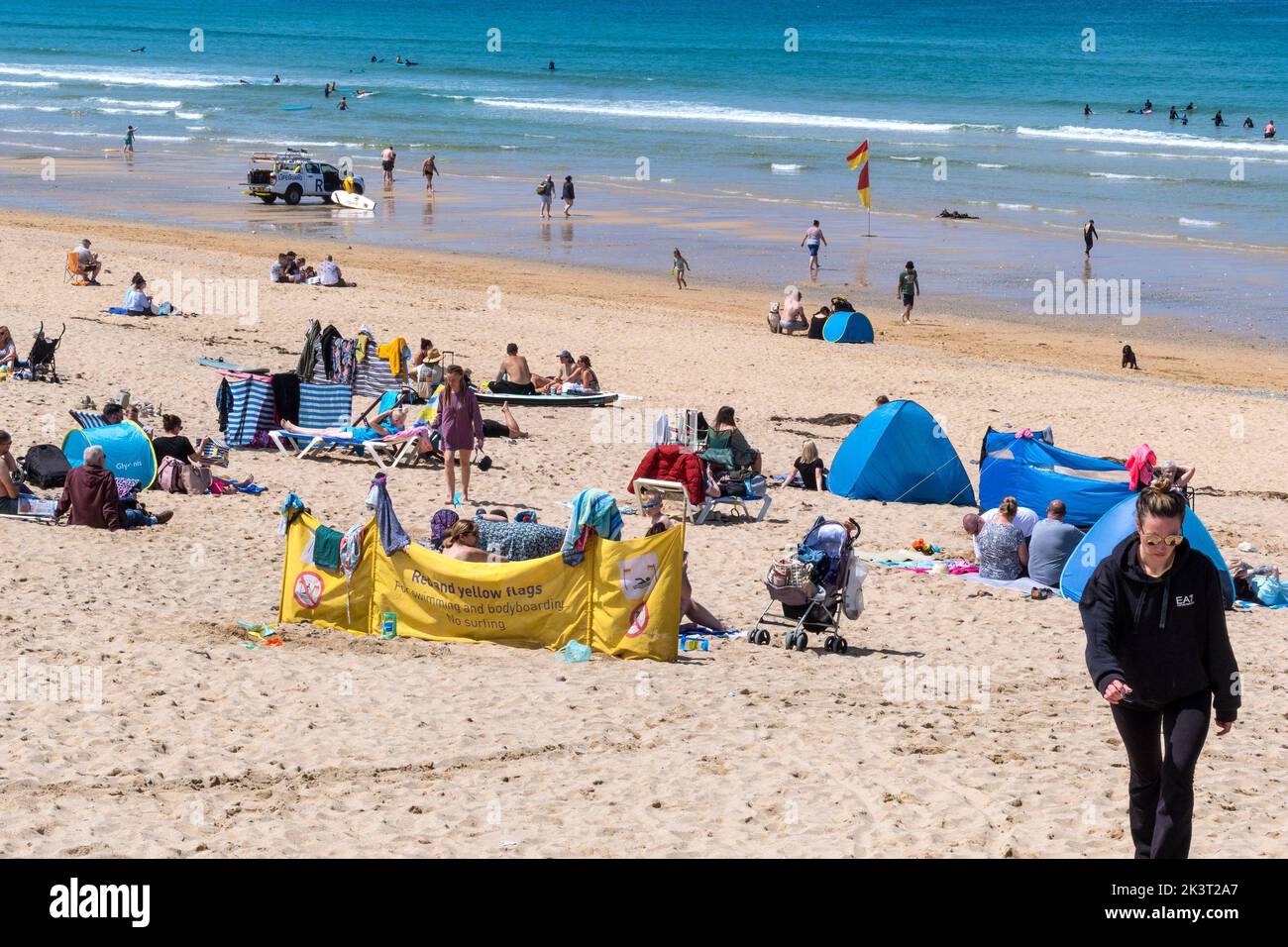 I turisti che si godono il caldo sole sulla Fistral Beach a Newquay in Cornovaglia nel Regno Unito. Foto Stock