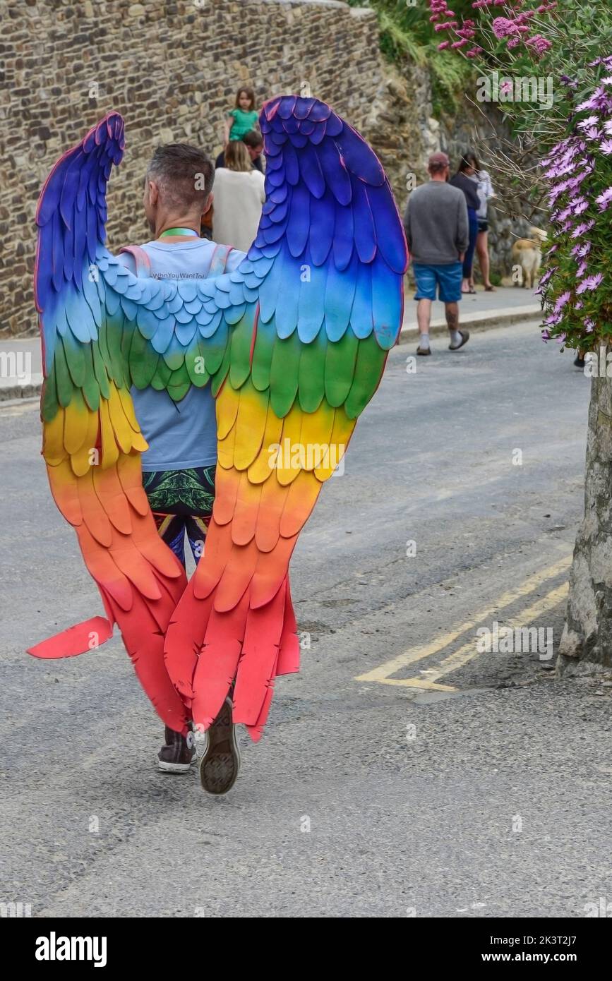 Un partecipante che indossa ali d'angelo colorate nella Cornovaglia è orgoglioso della sfilata Pride nel centro di Newquay nel Regno Unito. Foto Stock