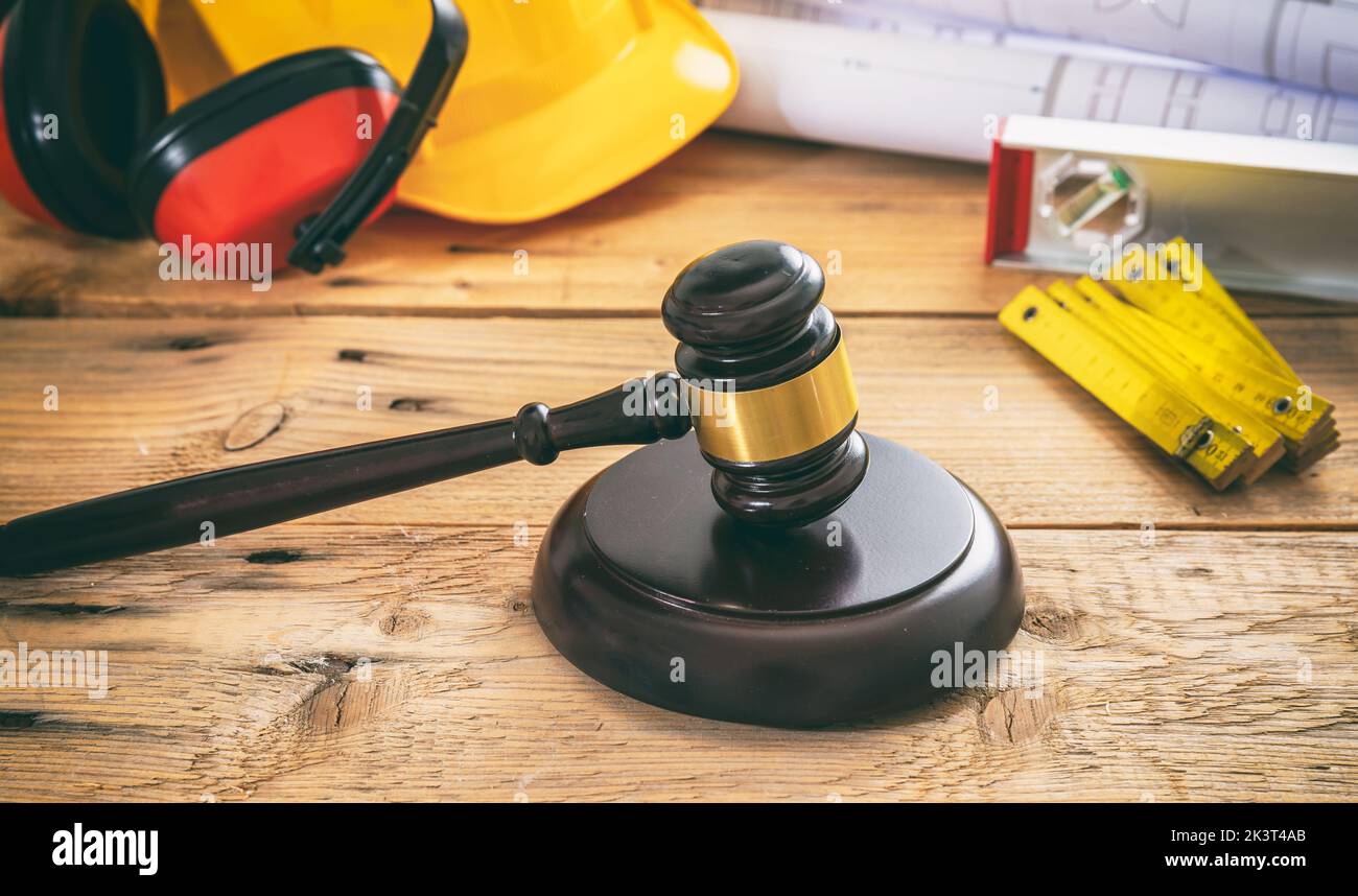 Costruzione e diritto del lavoro. Giudica il gavel e gli strumenti tecnici su un tavolo di legno, vista ravvicinata. Foto Stock