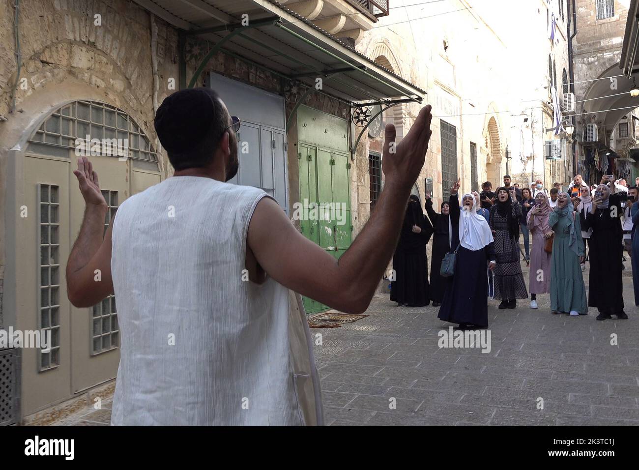 Un ebreo religioso cammina e grida in Chain Gate Street dopo una visita al monte del Tempio, mentre le donne palestinesi cantano il Takbir, che è il nome della frase araba 'Allahu Akbar' nella città vecchia il 27 settembre 2022 a Gerusalemme, Israele. Foto Stock