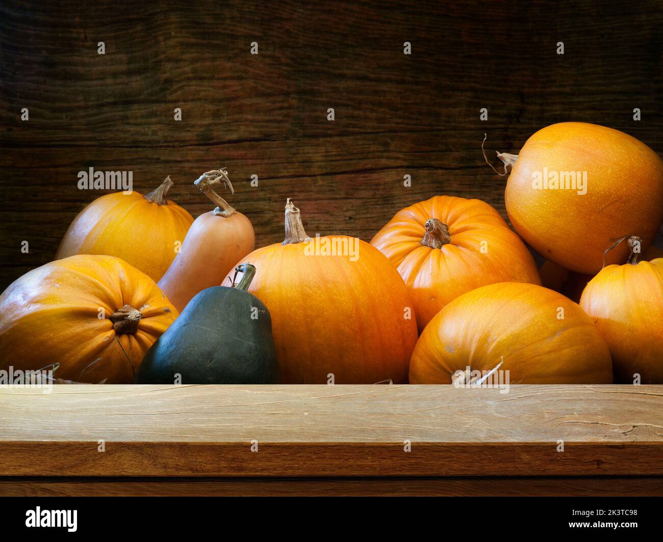 Tavolo di legno vuoto sullo sfondo della raccolta di zucca autunnale. Mockup per esterni per il design e l'esposizione dei prodotti. Foto Stock